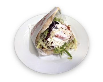 Döner im Fladenbrot mit Fleisch, Eisbergsalat, Rotkohl, Zwiebeln und Joghurtsauce auf einem weißen Teller