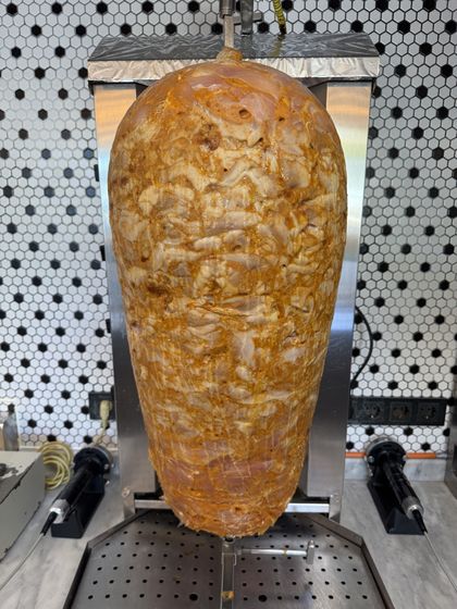 Frisch aufgesteckter Putenspieß mit heller Marinade, noch ungegart, zwischen den Grillflächen